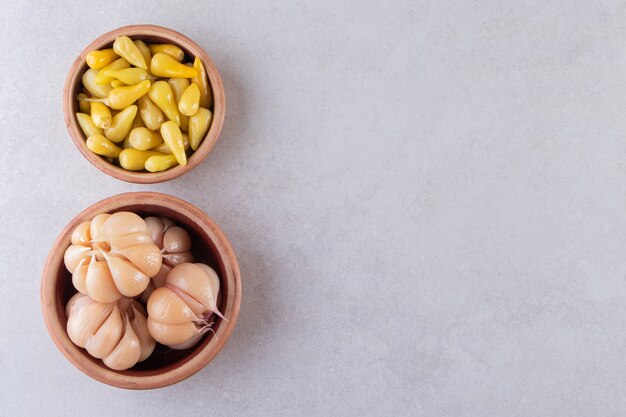 Smakelijke ingelegde knoflook in de kom die op steenachtergrond wordt geplaatst.