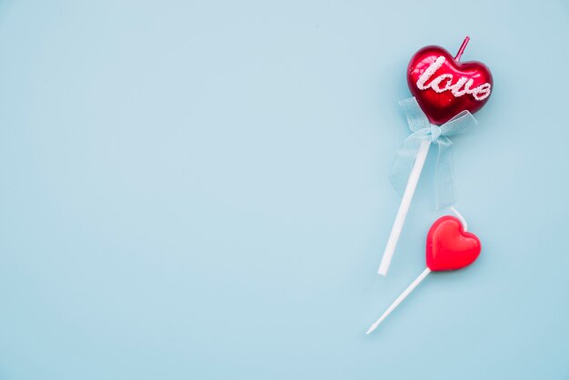 Smakelijke lolly en decoratieve kaars op toverstokken in de vorm van harten