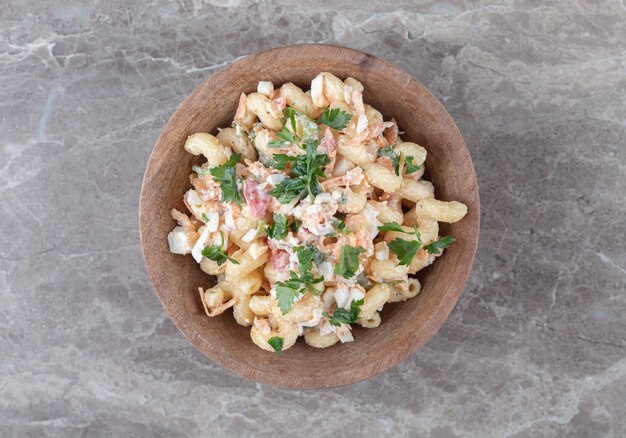 Smakelijke macaroni met gemengde salade in houten kom.