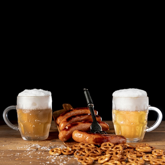 Smakelijke mokken bier met worstjes op een tafel