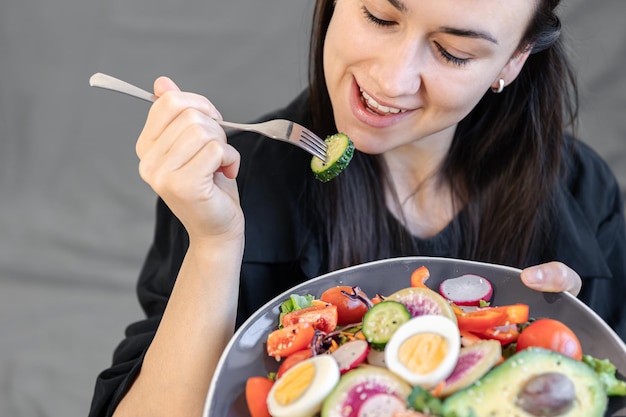 Smakelijke salade met verse groenten en eieren in een bord in vrouwelijke handen