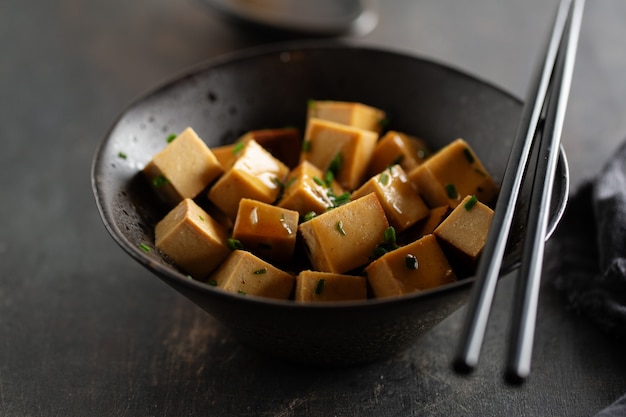 Gratis foto smakelijke smakelijke stukjes tofu met saus geserveerd in kom klaar om te eten. detailopname.