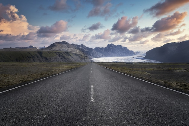 Smalle weg die leidt naar hoge rotsachtige bergen in het Nationaal Park Skaftafell in IJsland