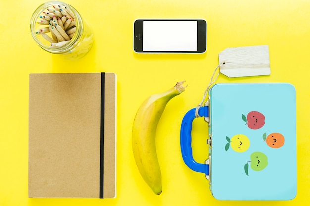 Smartphone in de buurt van lunchbox en briefpapier