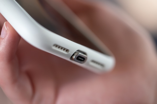 Smartphone met een close-up van de magnetische verbindingskabel in vrouwelijke handen.