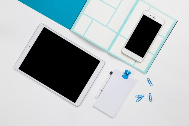 Smartphone met tablet en papier op tafel
