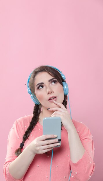 Smartphone van de vrouwenholding en het luisteren aan muziek op hoofdtelefoons