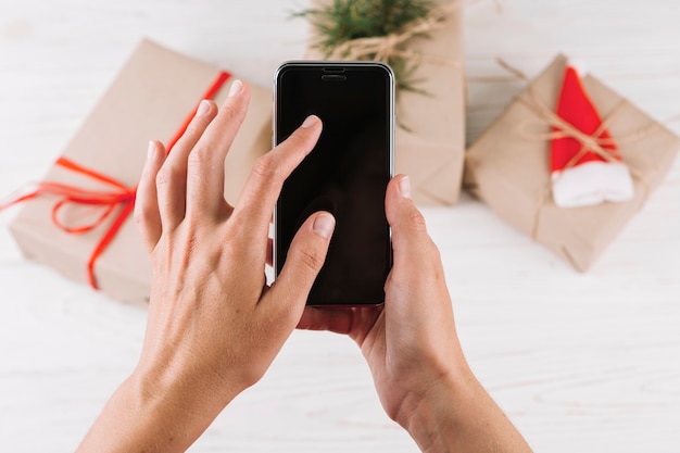 Gratis foto smartphone van de vrouwenholding voor giftdozen