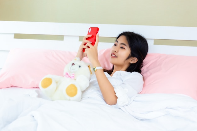 Smartphone van het tiener de vrouwelijke gebruik op het bed