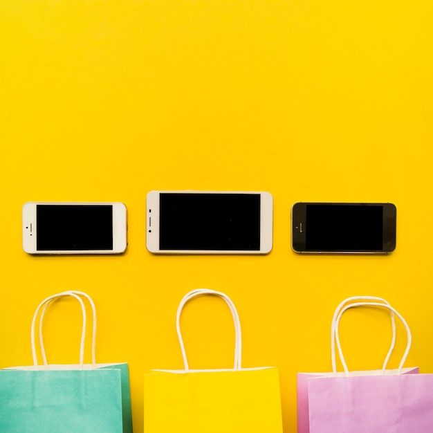 Smartphones met boodschappentassen op gele tafel