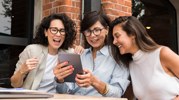 Smiley bedrijfsvrouwen die op een tablet kijken