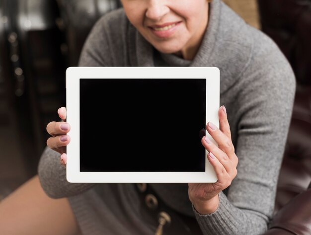 Smiley hogere vrouw die een lege tablet houdt