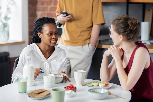 Gratis foto smiley huisgenoten aan tafel aan het kletsen