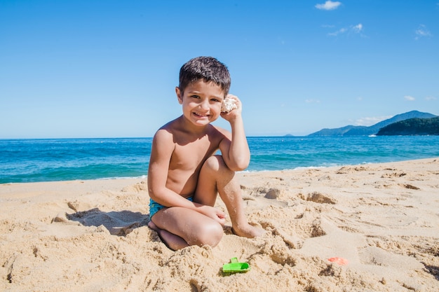 Smiley jongen met schelp op de zomer