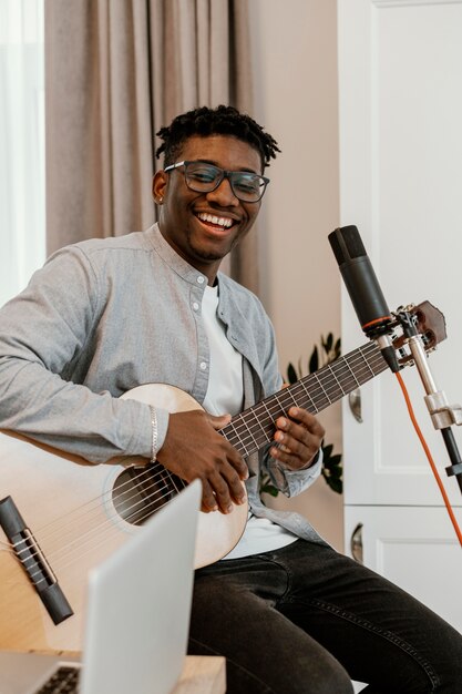 Smiley mannelijke muzikant thuis gitaar spelen en zingen