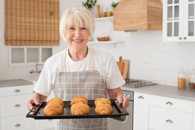 Smiley oude vrouw met dienblad met croissants