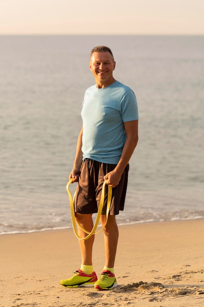 Smiley oudere man met elastisch touw op het strand