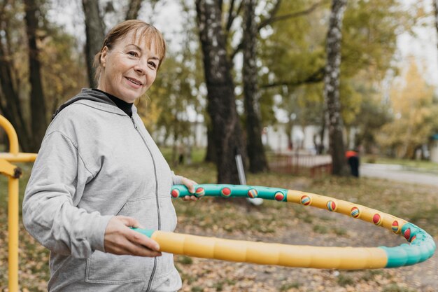 Smiley oudere vrouw buitenshuis uit te werken met apparatuur