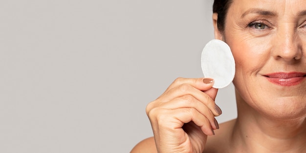 Smiley oudere vrouw poseren met wattenschijfje voor make-up verwijderen en kopie ruimte