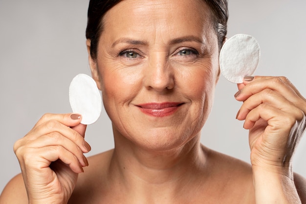 Smiley rijpe vrouw poseren met wattenschijfjes voor make-up verwijderen