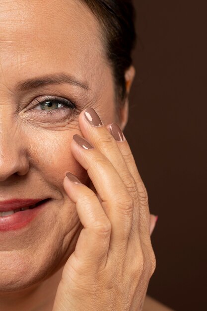 Smiley rijpe vrouw pronken met de helft van haar gezicht met make-up op