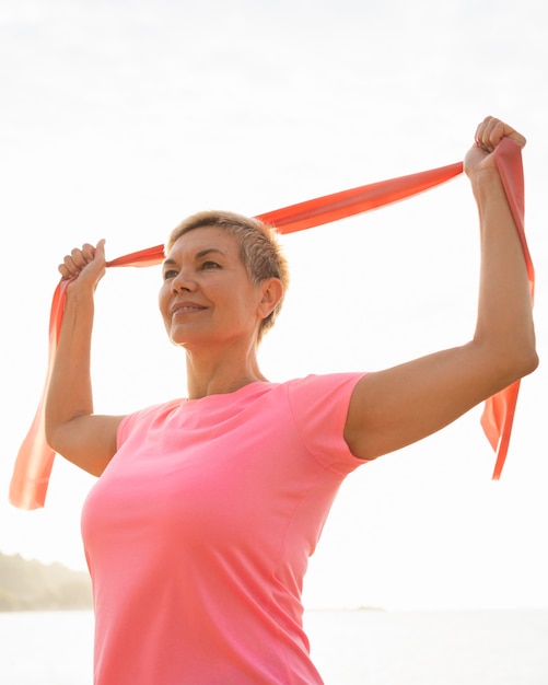 Gratis foto smiley senior vrouw met elastisch touw op het strand