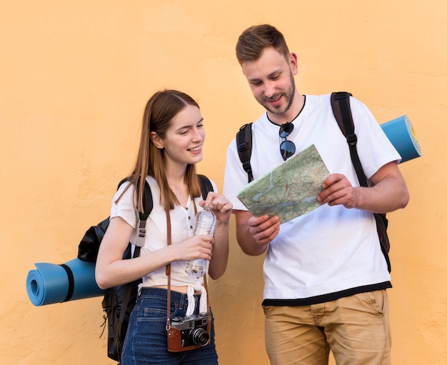 Gratis foto smiley toeristenpaar met rugzakken en kaart