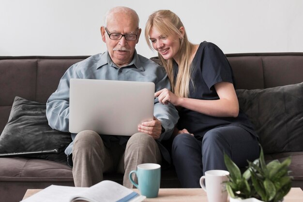 Smiley verpleegster die oude man laptop toont