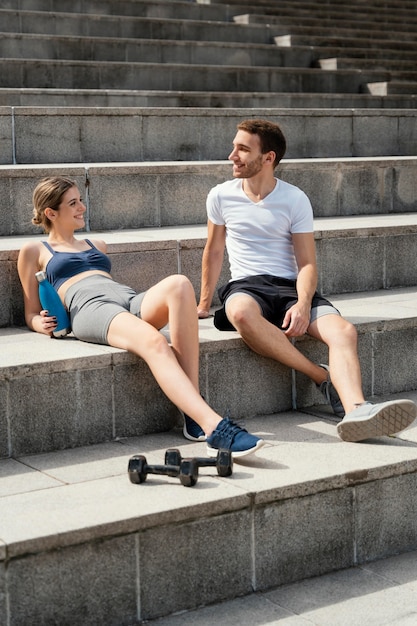 Smiley vrouw en man rusten op trappen tijdens het sporten