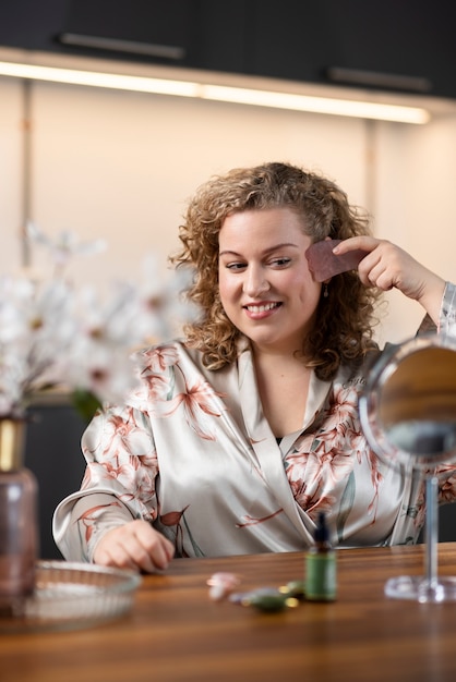 Smiley vrouw gezicht masseren met gua sha medium shot