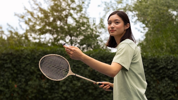 Gratis foto smiley vrouw met racket zijaanzicht