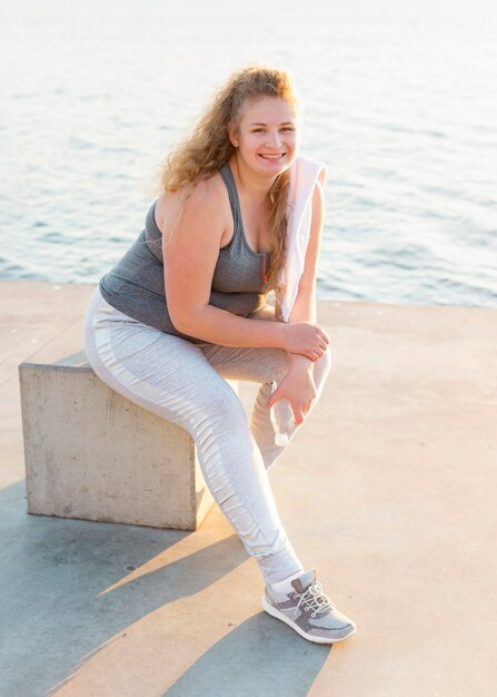 Smiley vrouw poseren aan het meer na het trainen