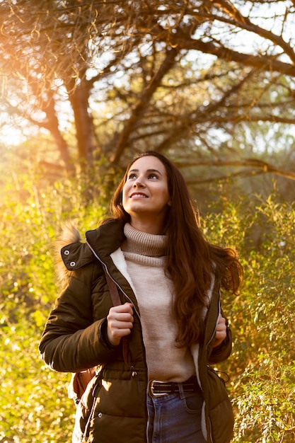 Smiley vrouw poseren in de zon tijdens het verkennen van de natuur