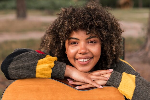 Smiley vrouw poseren met gitaar tijdens het kamperen buiten