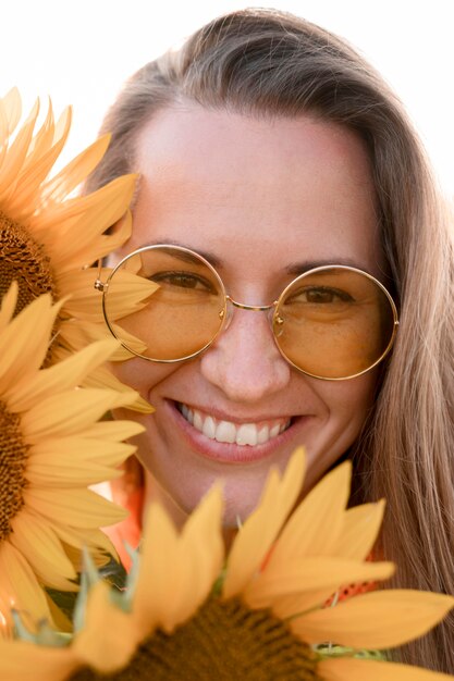 Gratis foto smiley vrouw poseren met zonnebloemen