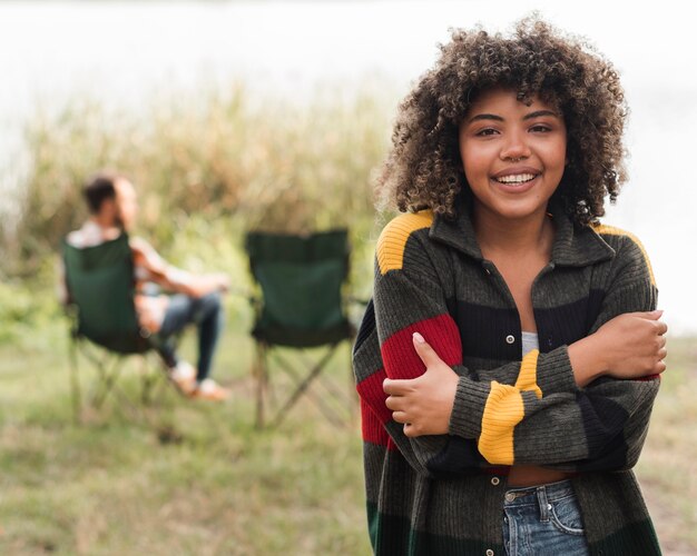 Smiley vrouw poseren terwijl vriendje ontspannen op stoel buitenshuis