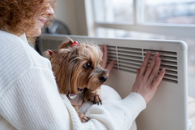 Smiley vrouw zit in de buurt van verwarming met hond