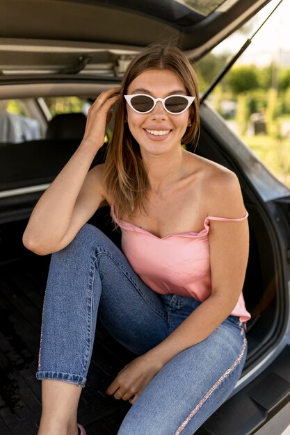 Smiley vrouw zittend op een auto kofferbak