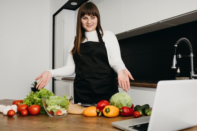 Smiley vrouwelijke blogger streaming koken met laptop thuis