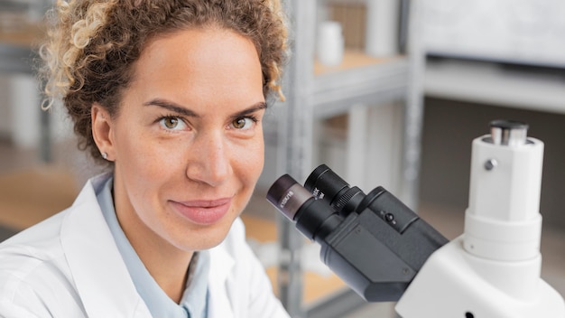 Smiley vrouwelijke onderzoeker in het laboratorium met behulp van Microscoop