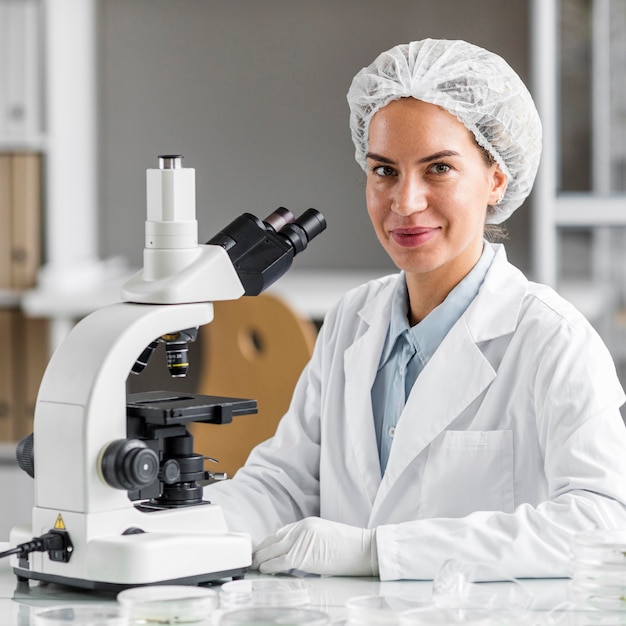 Smiley vrouwelijke onderzoeker in het laboratorium voor biotechnologie met Microscoop