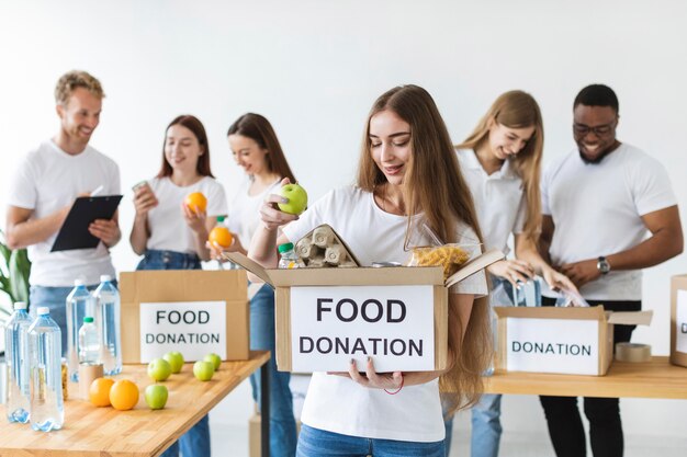 Smiley vrouwelijke vrijwilliger bedrijf doos met donaties