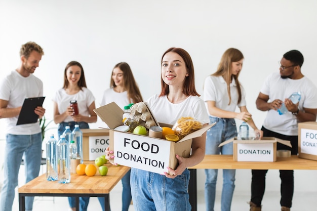 Gratis foto smiley vrouwelijke vrijwilliger donatiebox met voedsel te houden