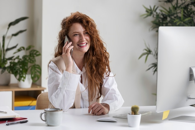 Smiley zakenvrouw bij bureau zijaanzicht