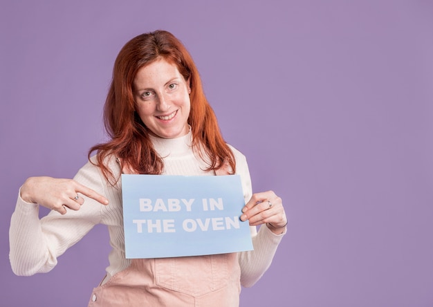 Smiley zwangere vrouw die op baby in het ovenbericht richt