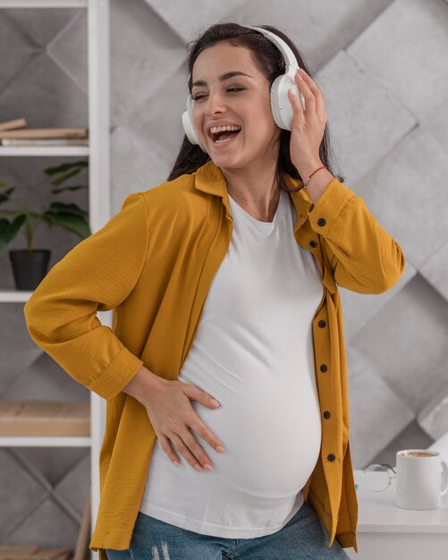 Smiley zwangere vrouw die van muziek op hoofdtelefoons geniet