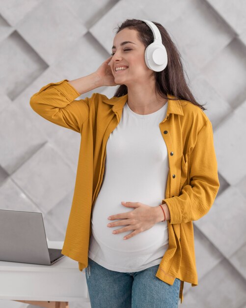 Smiley zwangere vrouw luisteren naar muziek op de koptelefoon
