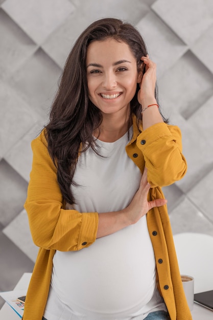 Smiley zwangere vrouw poseren thuis