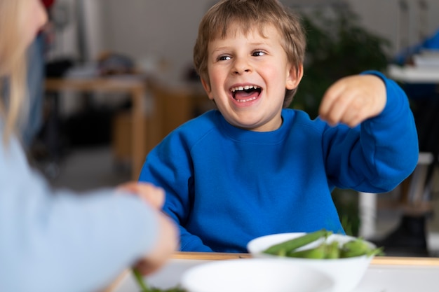 Gratis foto smileykind met sperziebonen binnenshuis