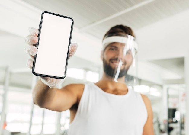 Smileymens met gezichtsschild bij de smartphone van de gymnastiekholding